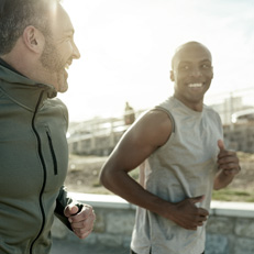 2 runners smile at eachother in the sun, while on a jog
