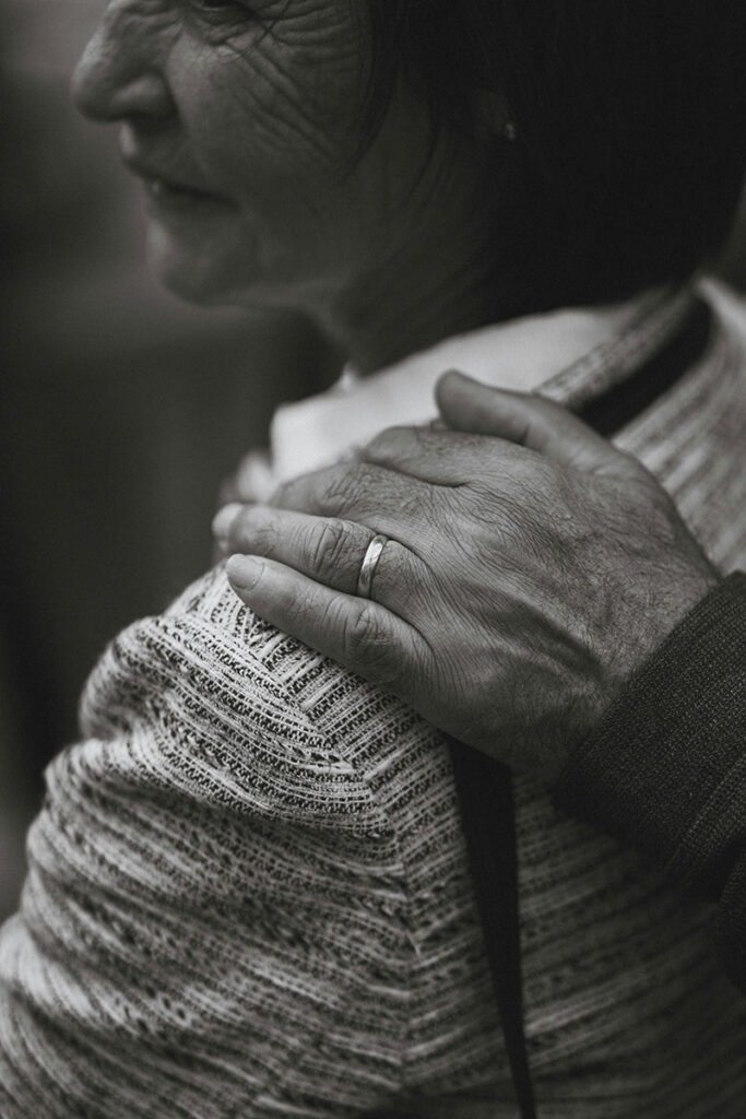 elderly woman with person's hand on her shoulder
