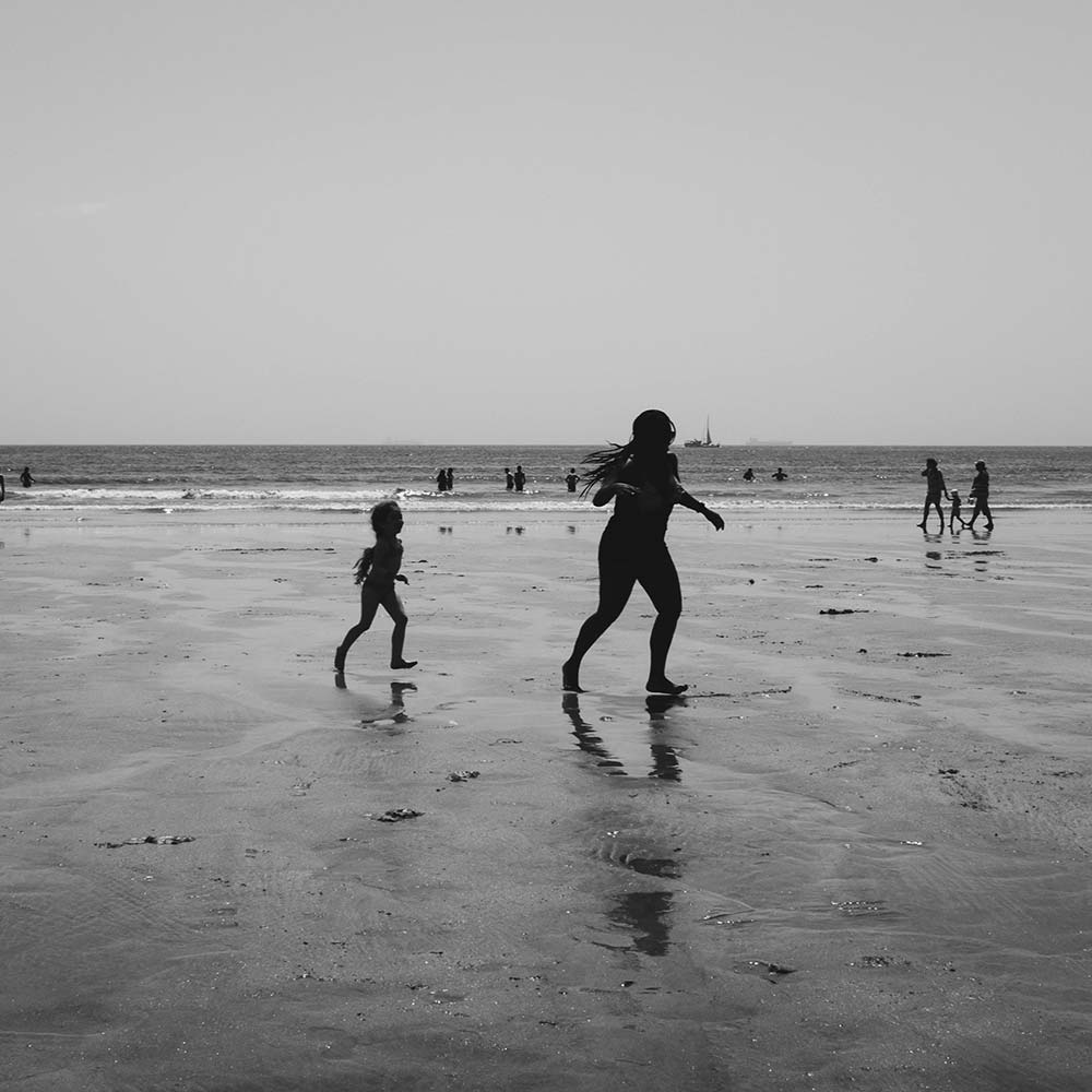 Grayscale photo of mother and daughter on the beach