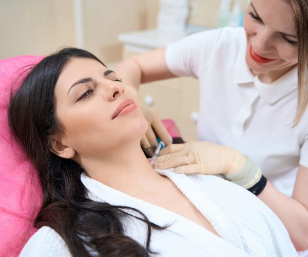 Female patient undergoing neck mesotherapy procedure by doctor Beautiful woman during skin mesotherapy procedure by smiling doctor in aesthetic medicine