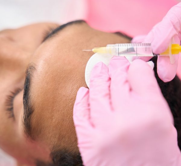 Closeup of young male patient undergoing mesotherapy procedure conducted by qualified dermatologist in nitrile gloves